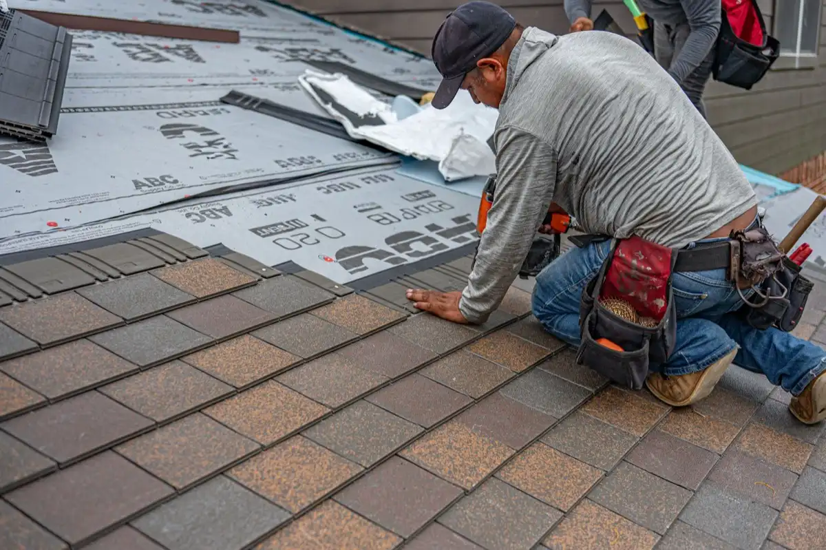 Roofing installer fastening shingles over new underlayment in Alpharetta, GA